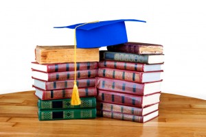 Graduation mortarboard on top of stack of books on white isolate