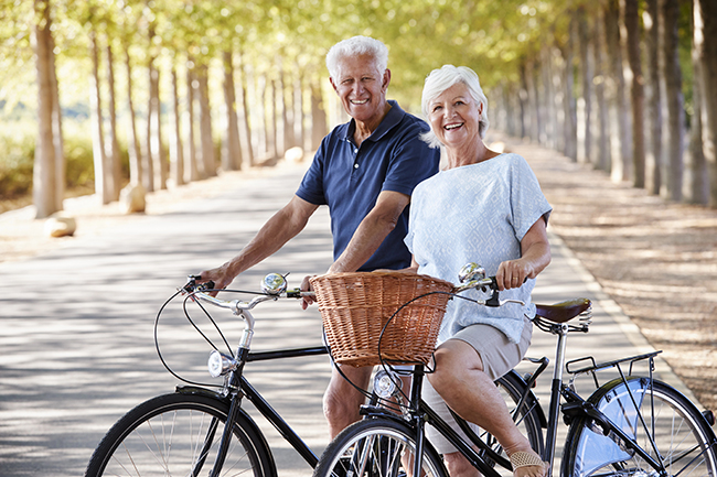 Active senior couple riding bikes together outdoors at a retirement community