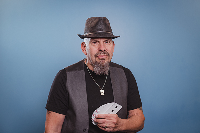 Magician David holding playing cards; lives with Parkinson’s disease and uses magic to maintain dexterity