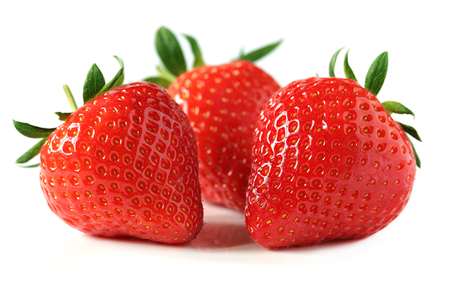 Three ripe red strawberries with green leaves