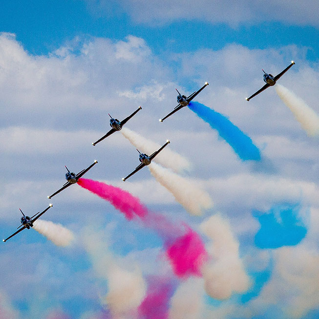 Air show planes flying in formation with colorful smoke trails
