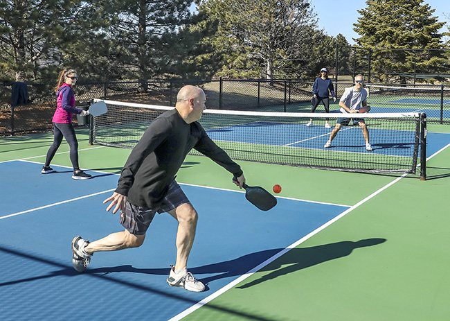 Adults playing pickleball on an outdoor court