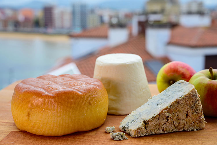 Selection of traditional Spanish cheeses from Asturias overlooking San Lorenzo Beach in Gijón, Spain